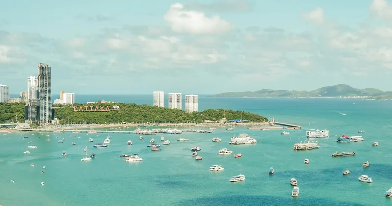 Boats across Pattaya Bay beneath the Pattaya City hillside sign.