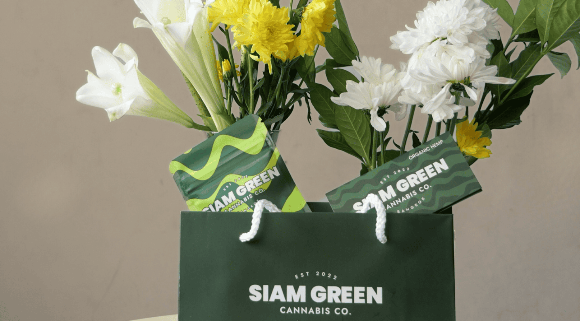 Siam Green Cannabis Co shopping bag with a bouquet of fresh flowers